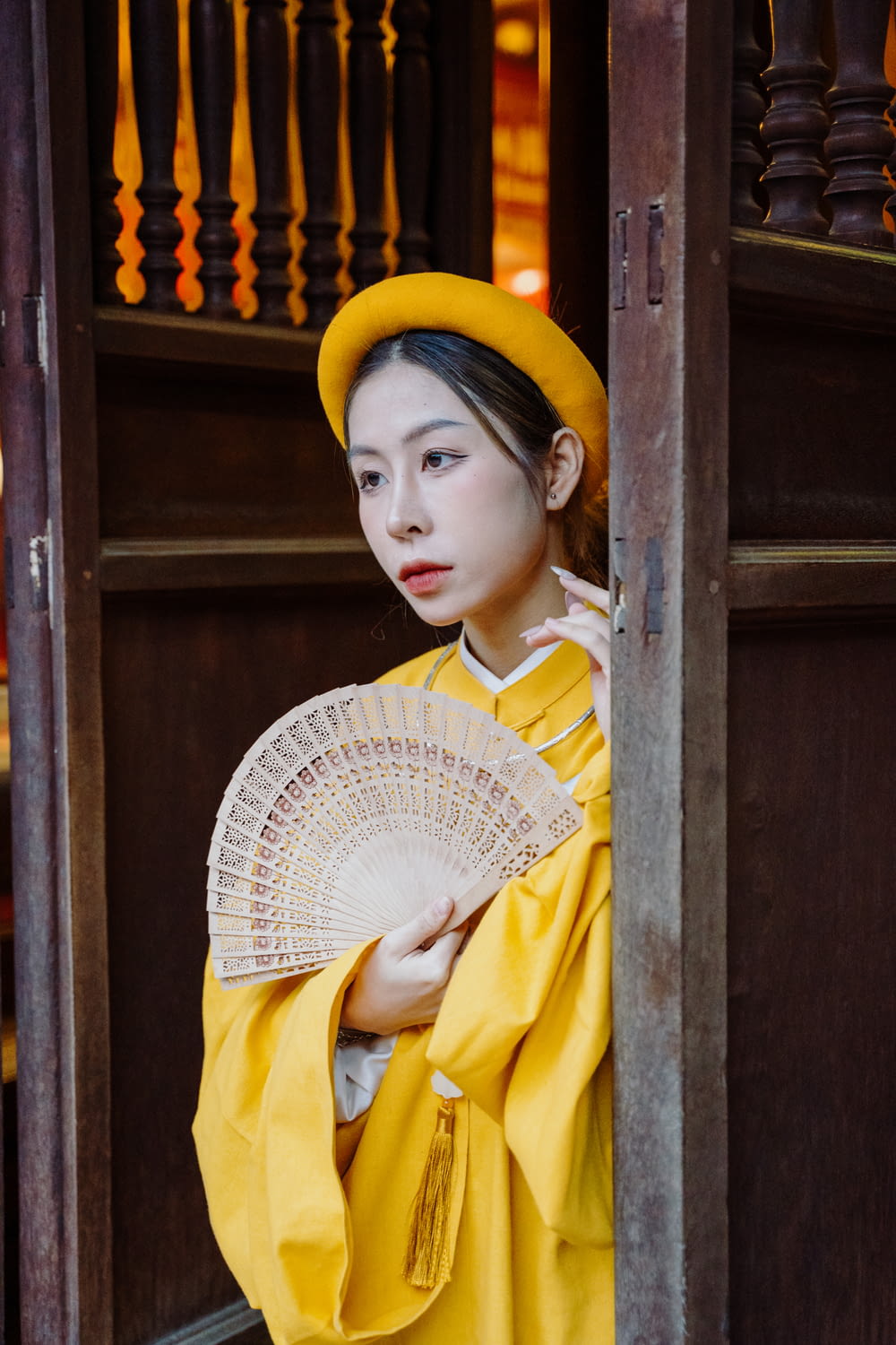 a woman in a yellow outfit holding a fan