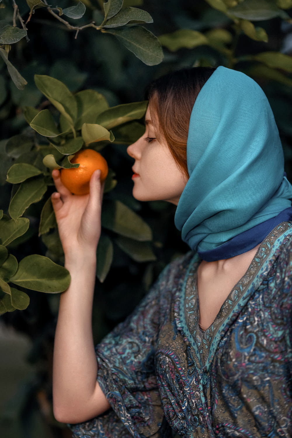 a woman in a headscarf is holding an orange