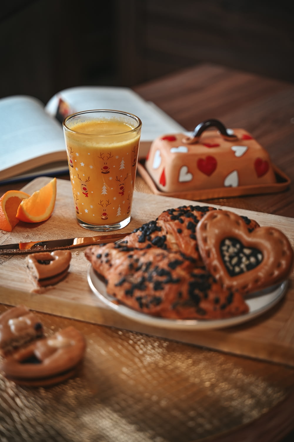 a wooden table topped with cookies and a glass of orange juice