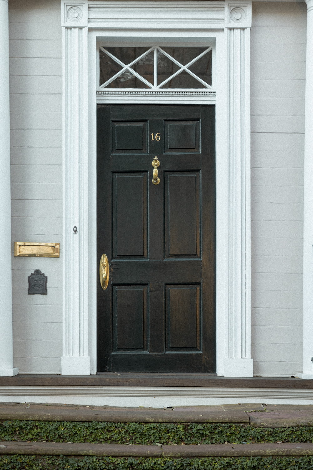 the front door of a white house with a black door