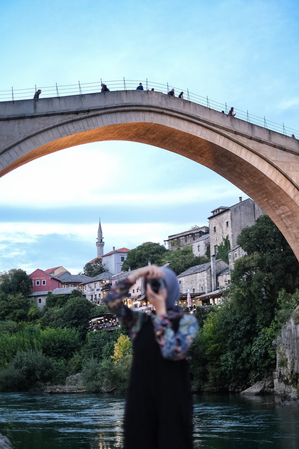 a woman standing under a bridge holding a camera