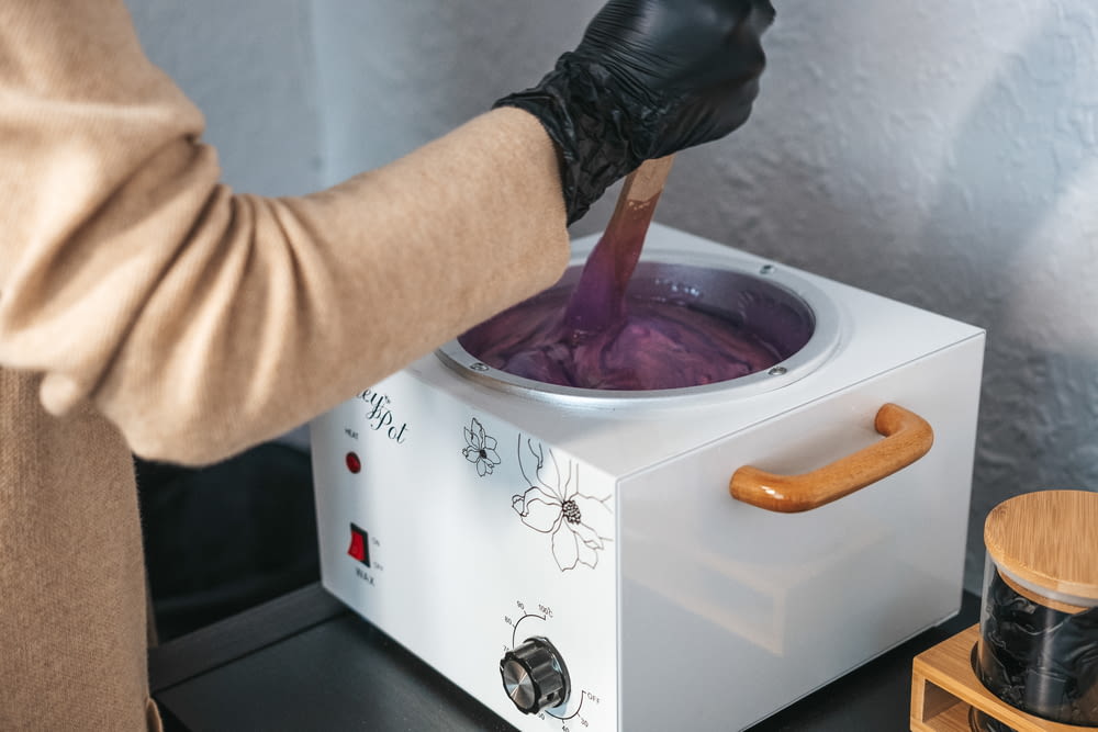 a person in black gloves stirring a pot of purple liquid