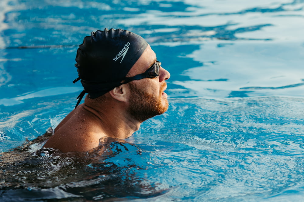 a man swimming in a pool wearing a swimming cap