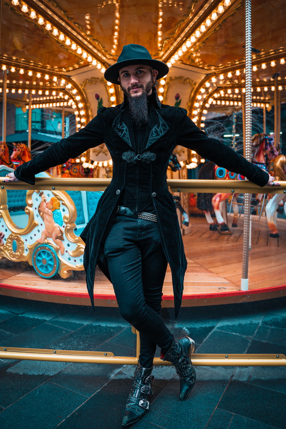 a man in a long coat and hat standing in front of a carousel