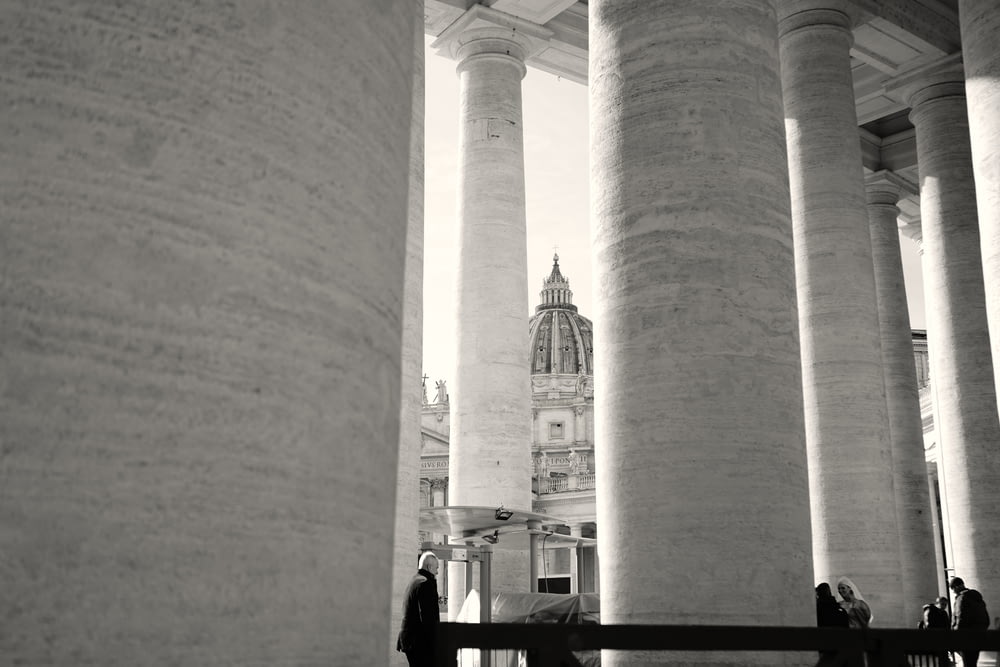 a black and white photo of columns and a clock tower