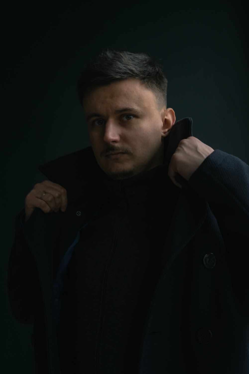 a man in a black coat posing for a picture