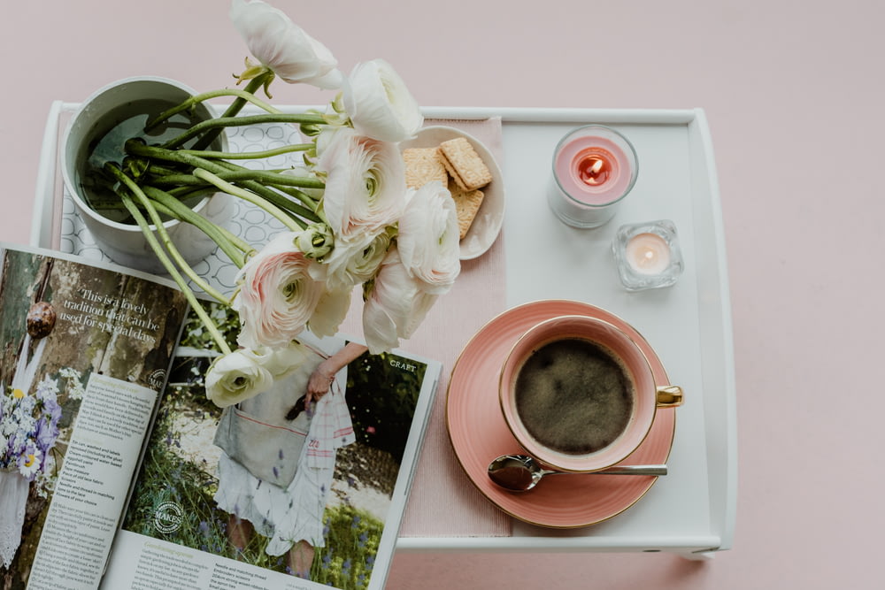 a table topped with a cup of coffee and a magazine