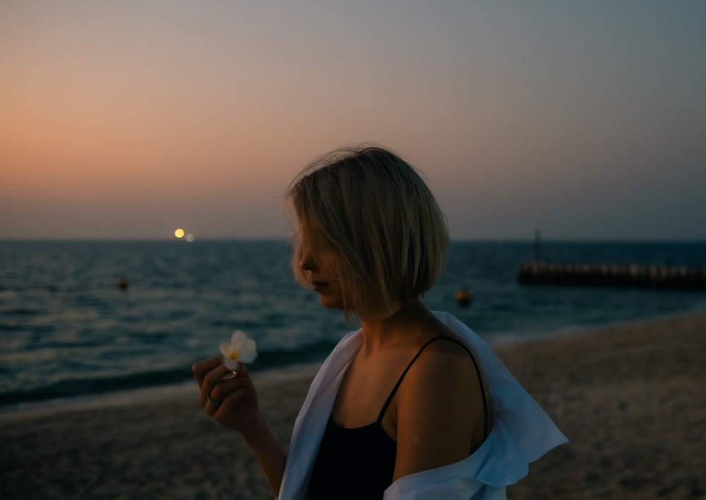 a woman standing on a beach eating a piece of food