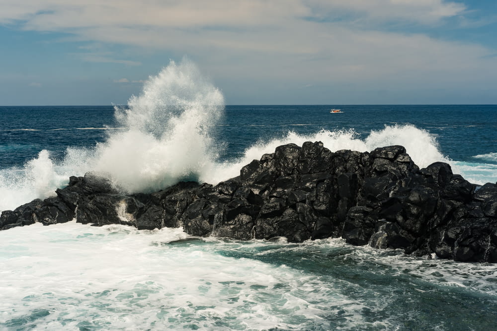 a large wave hitting on a rock in the ocean