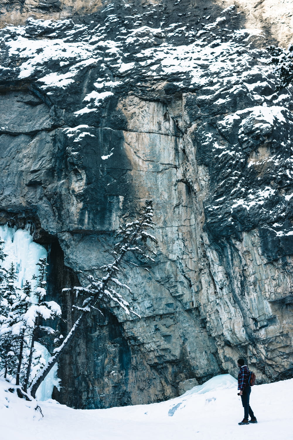 a person standing in the snow near a cliff