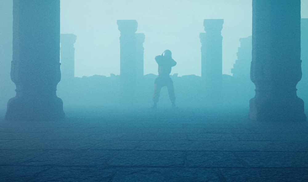a person standing in front of pillars in a foggy area