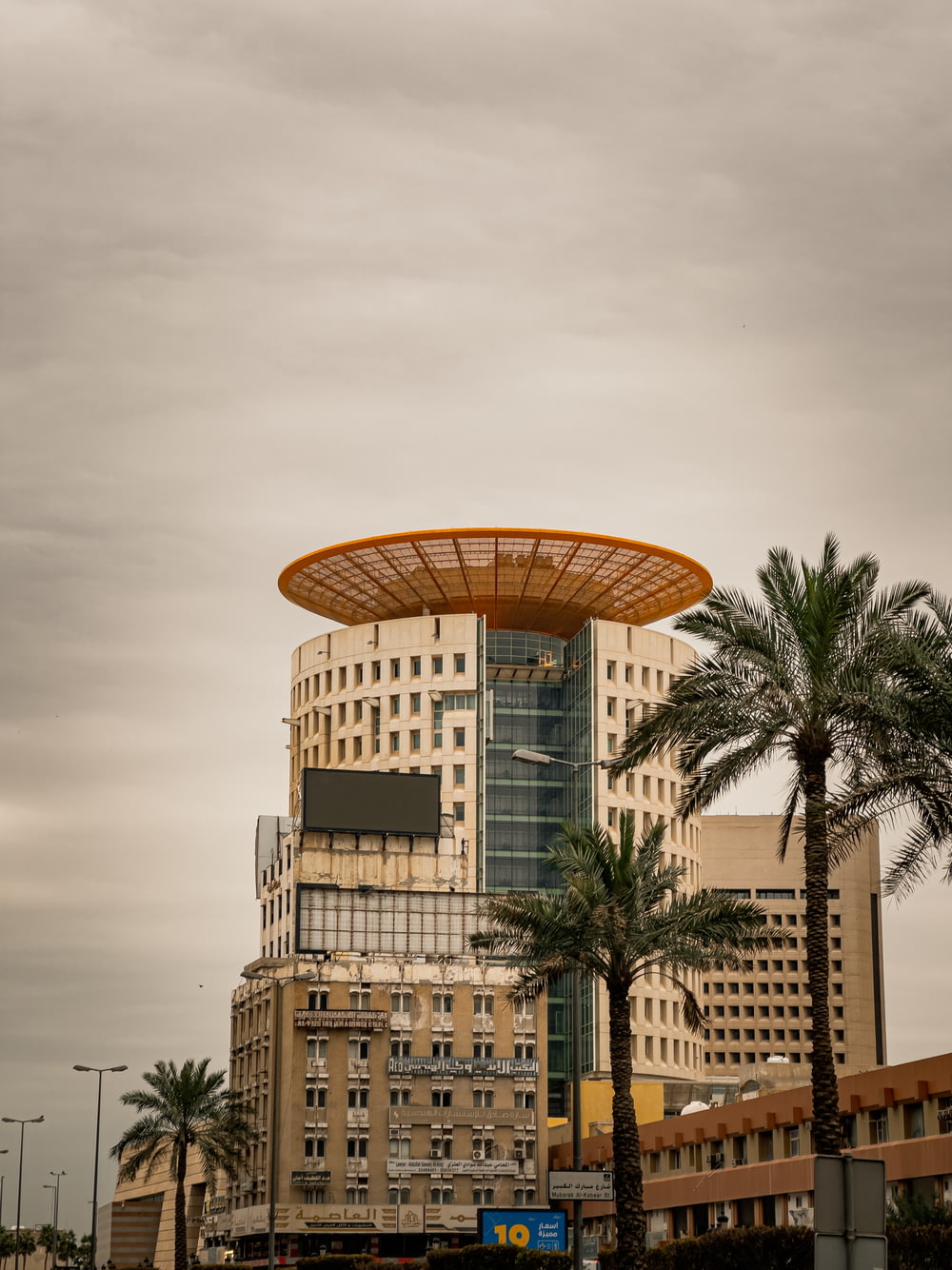 a tall building with a yellow roof and palm trees in front of it