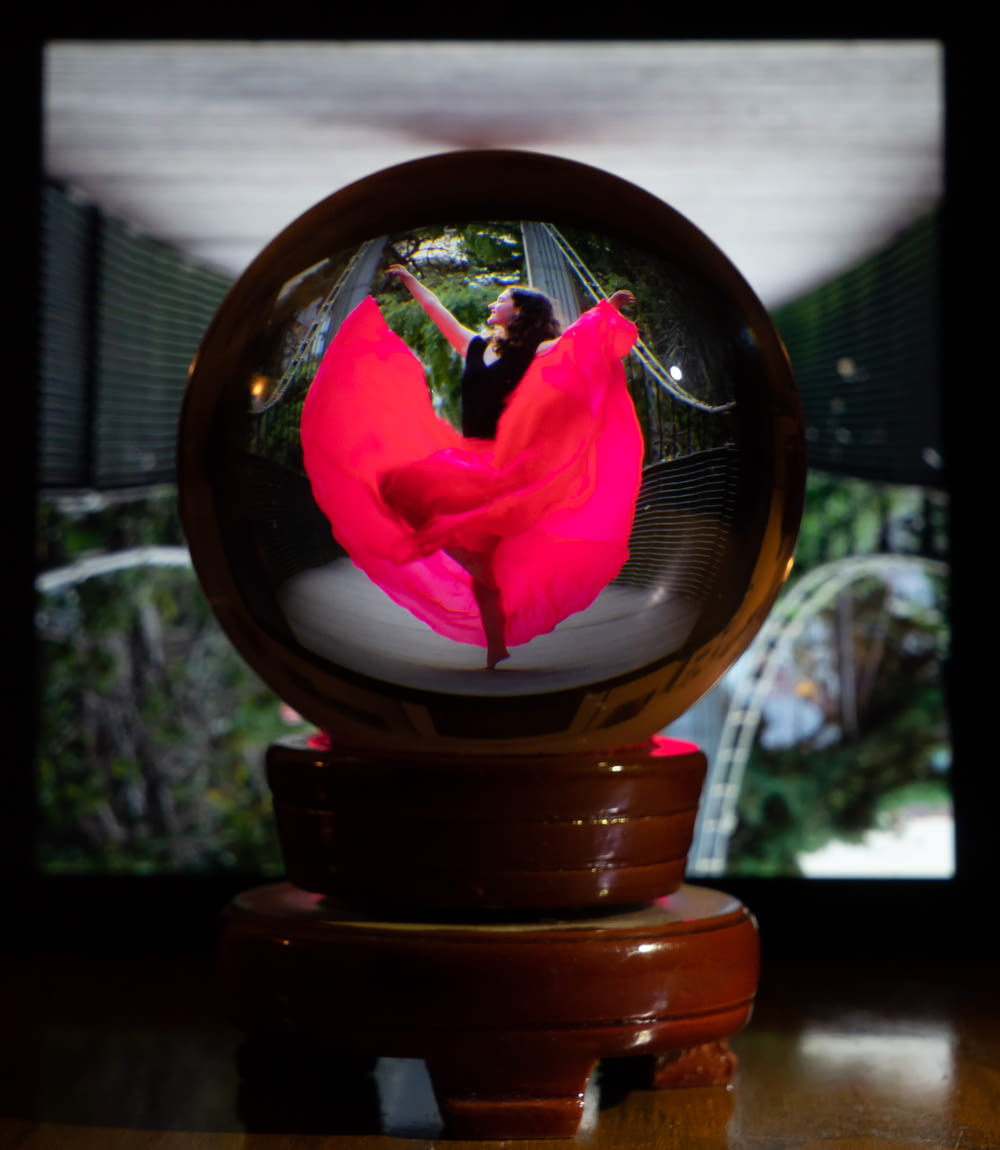 a woman in a red dress is dancing in a glass ball
