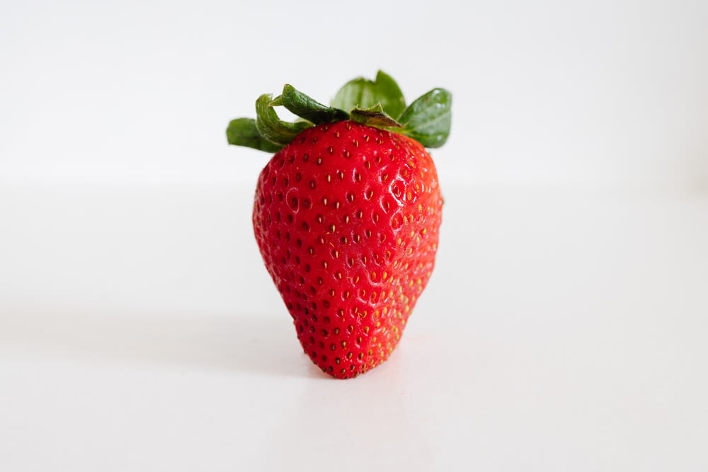 a close up of a strawberry on a white surface
