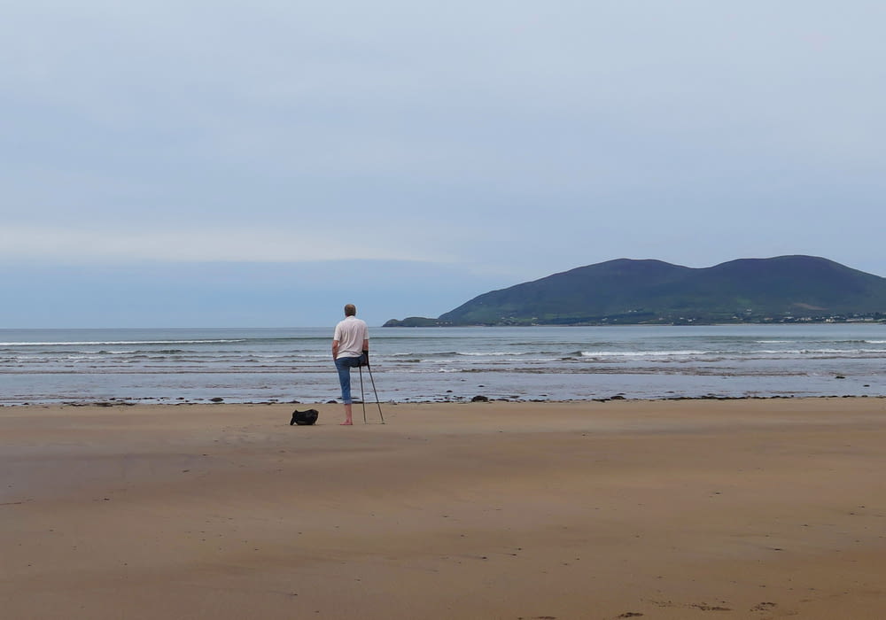 a man standing on top of a sandy beach next to the ocean