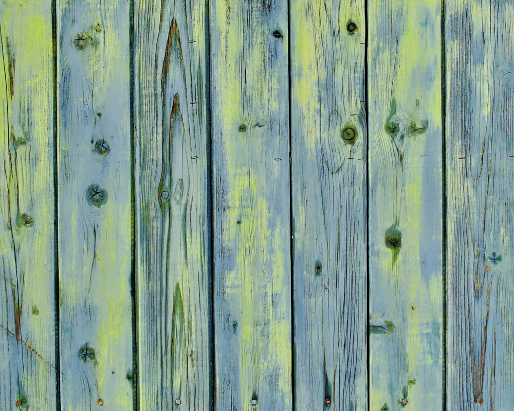 a close up of a wooden fence with green paint