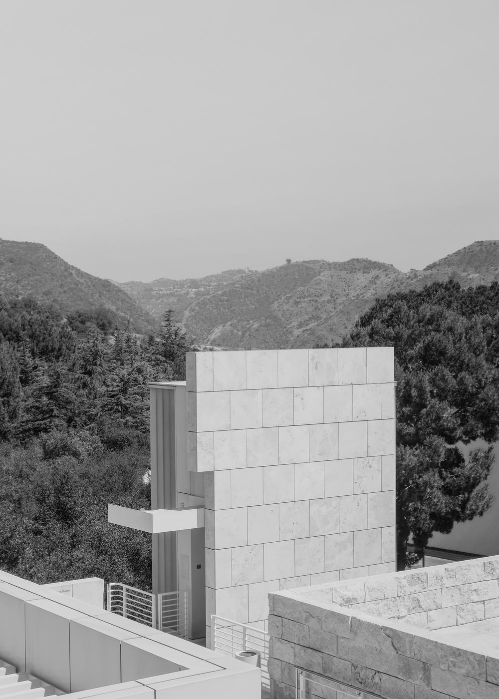 a black and white photo of a building with mountains in the background
