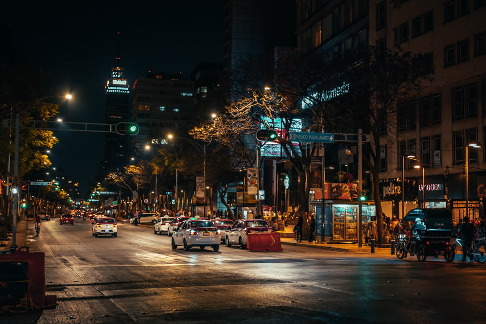 a city street at night with cars driving down it