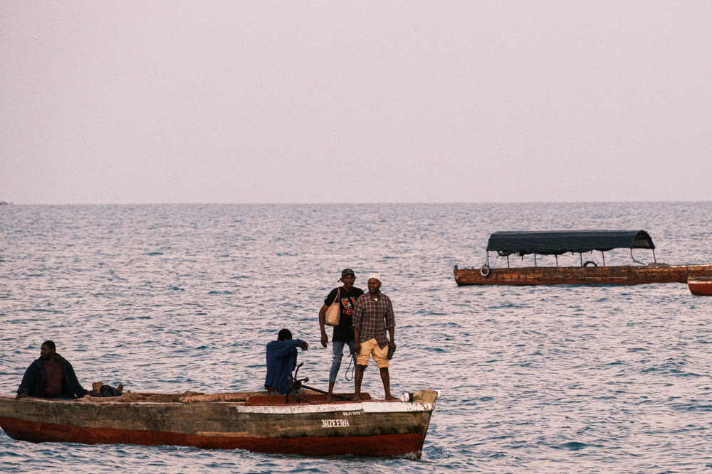 a group of men standing on top of a boat in the ocean
