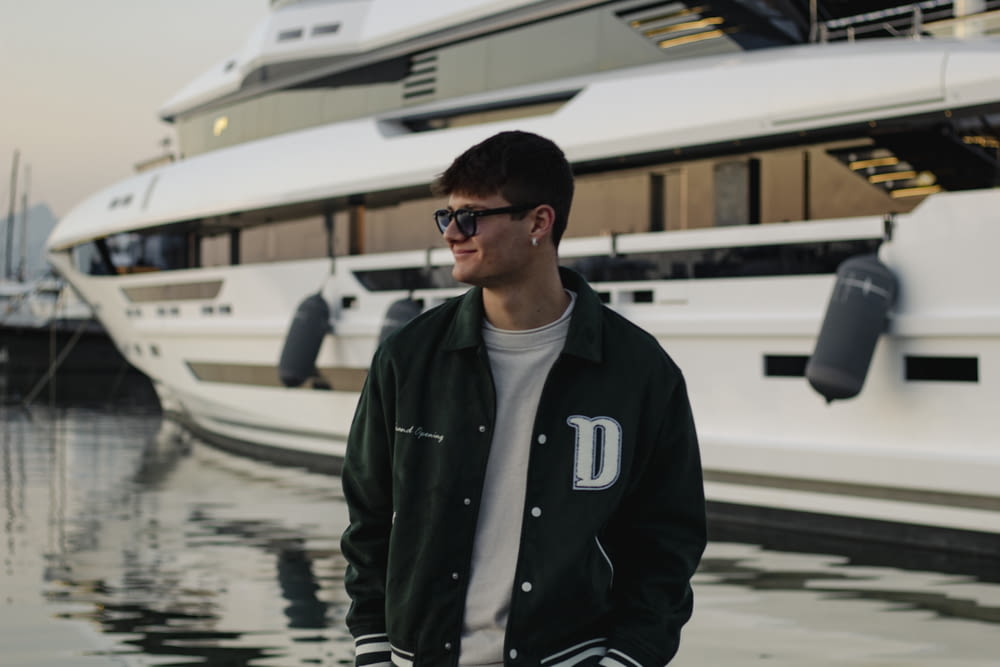 a man wearing sunglasses standing in front of a boat
