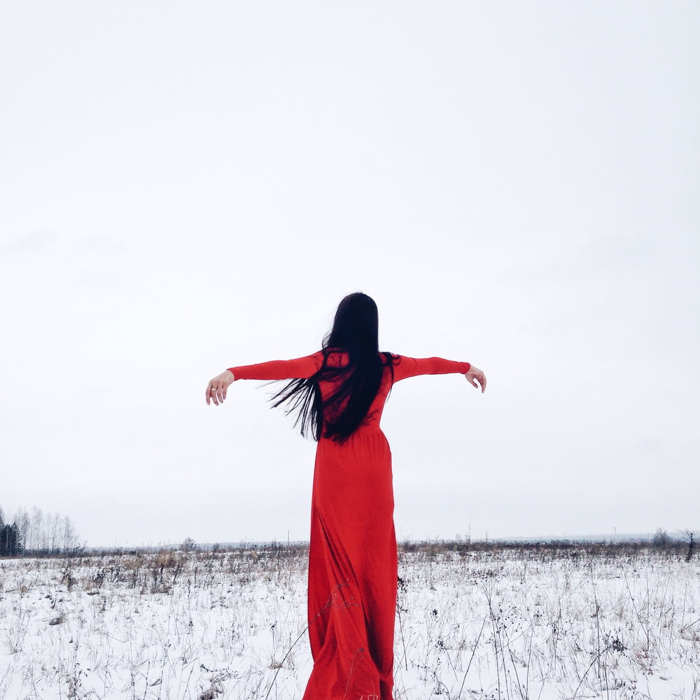 uma mulher em um vestido vermelho de pé na neve