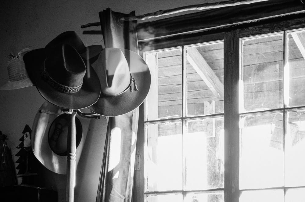 a black and white photo of hats hanging on a wall