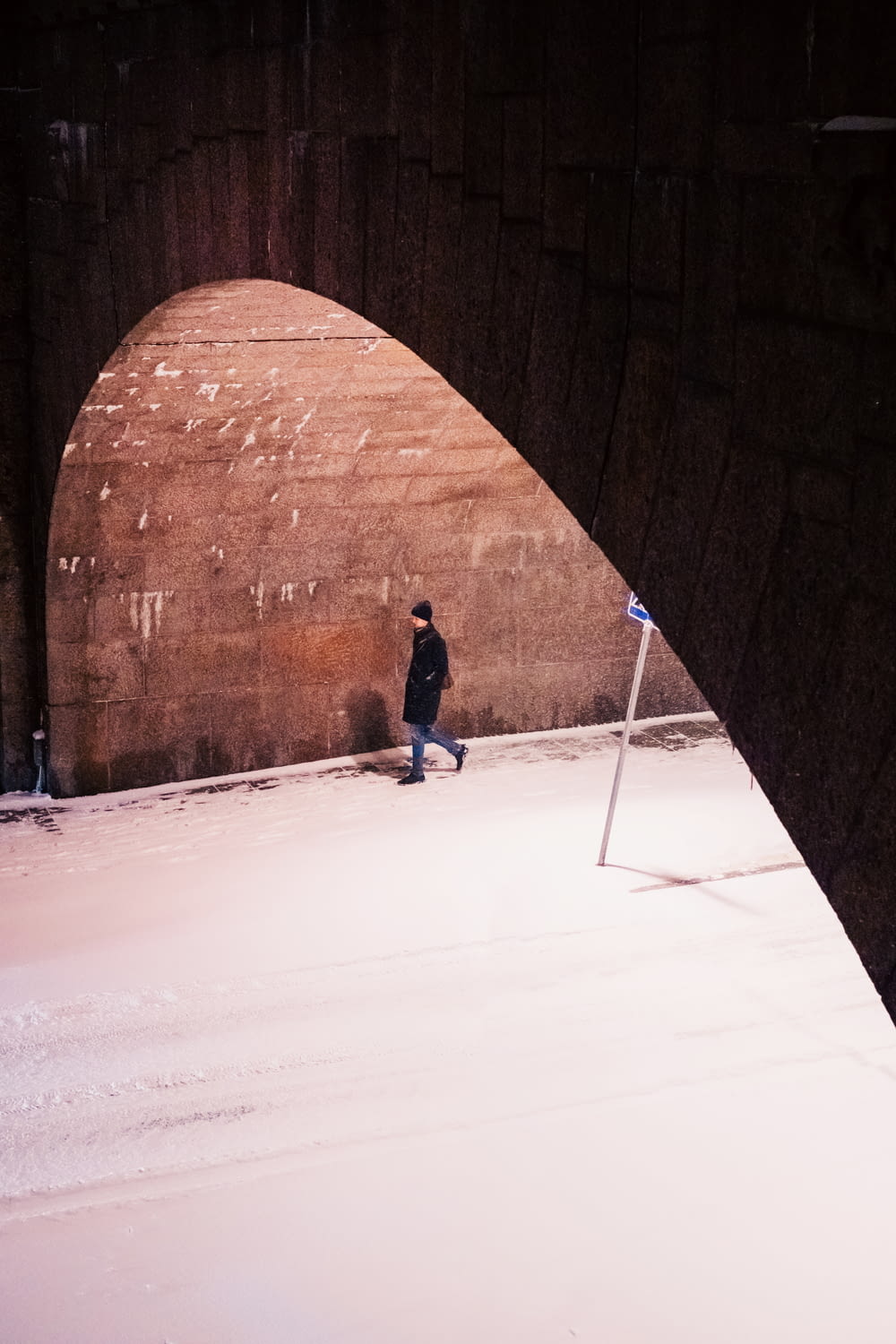 a person walking under a bridge in the snow