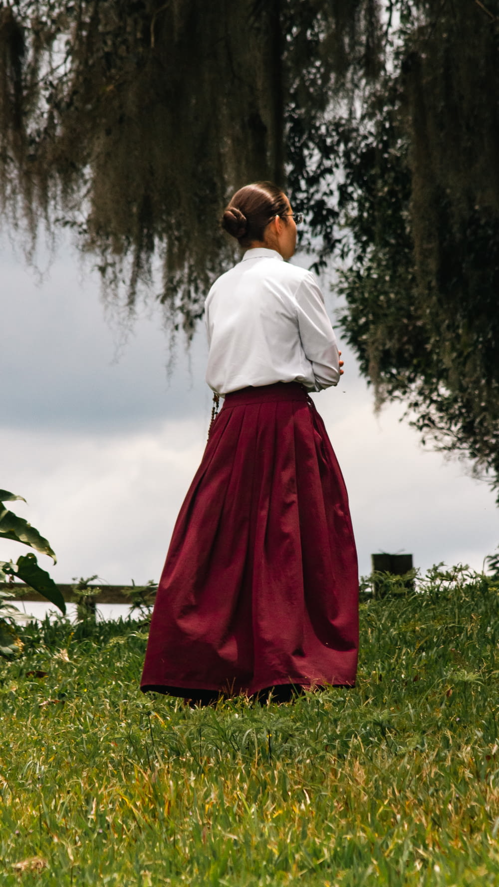 a woman in a long skirt standing in the grass