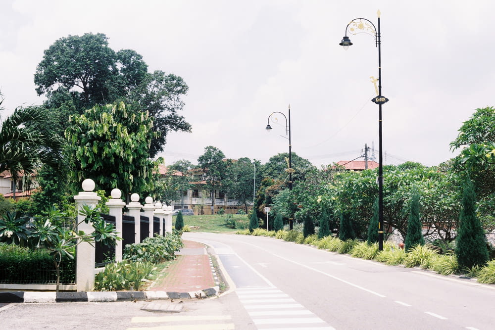 a street with a white fence and trees