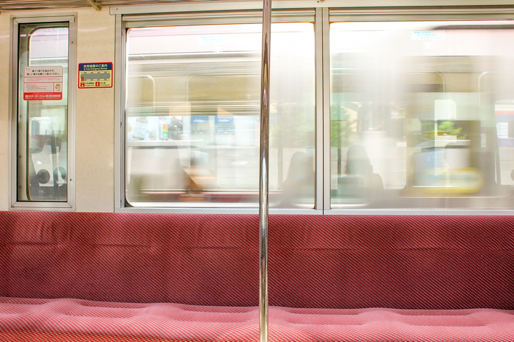 Un banco rojo sentado junto a una ventana en un tren