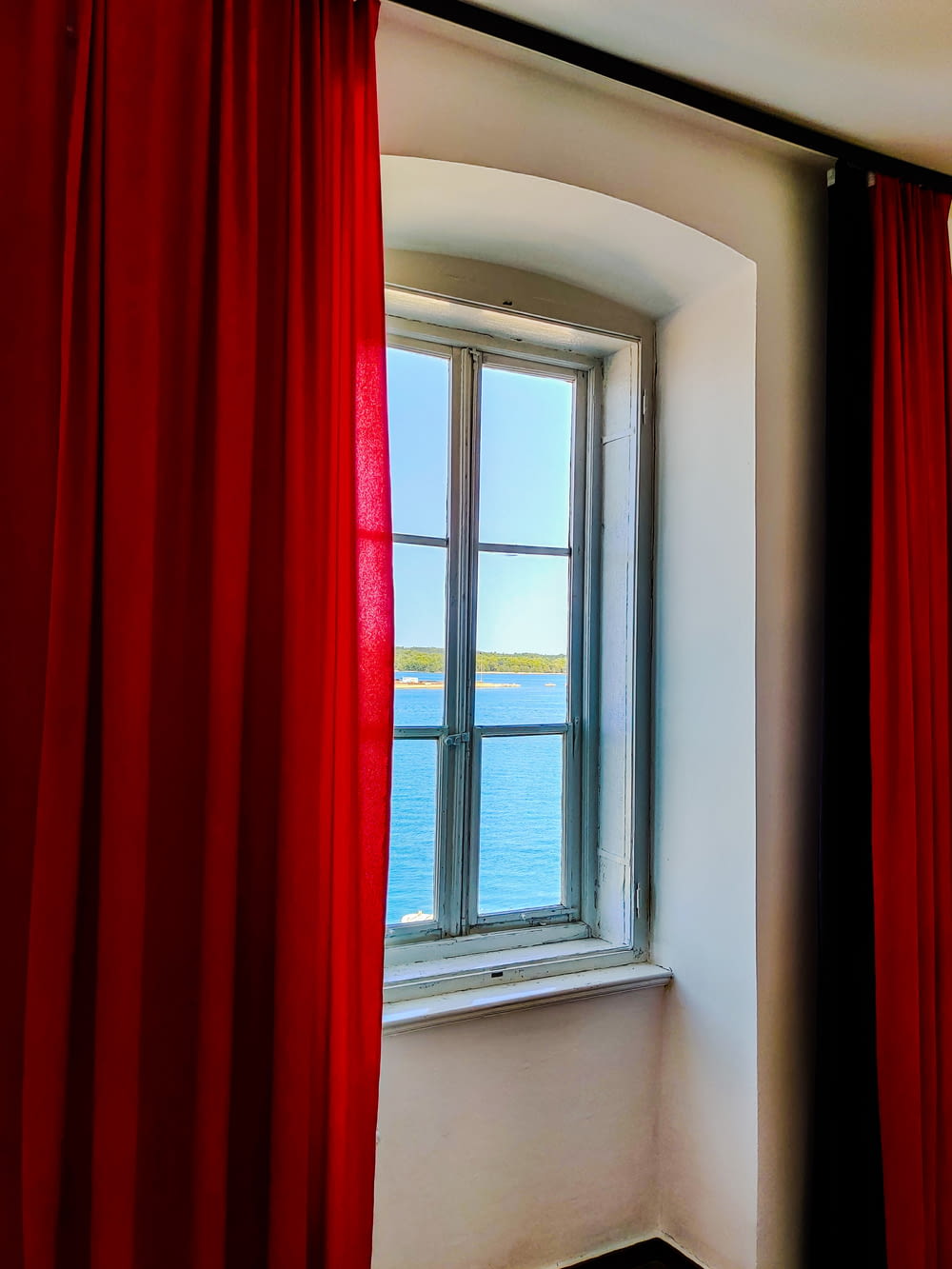 赤いカーテンと海の景色を望む窓