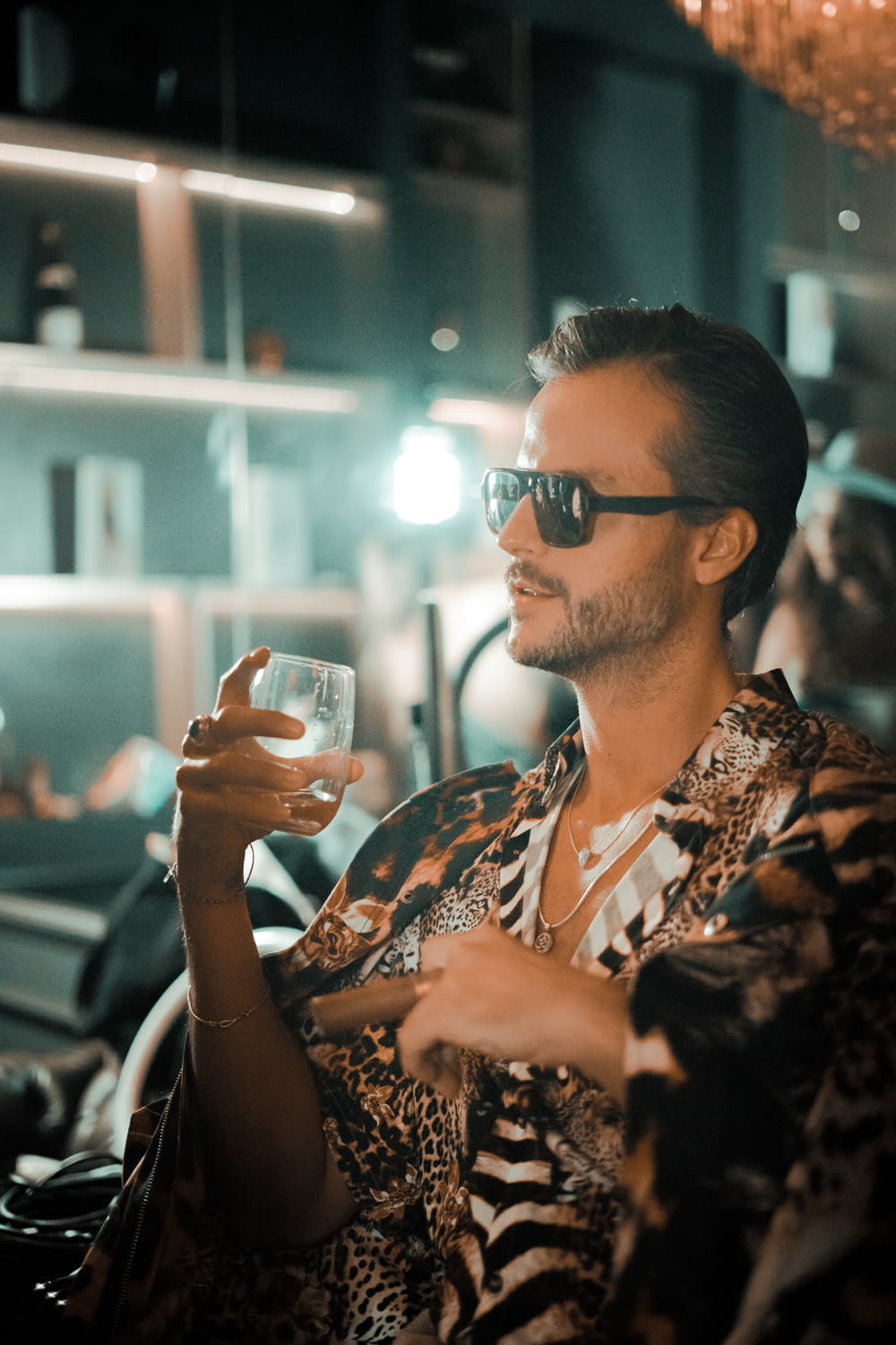 a man wearing sunglasses holding a glass of wine