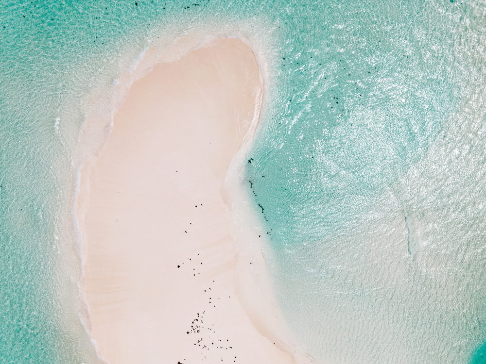 an aerial view of a sandy beach and turquoise water