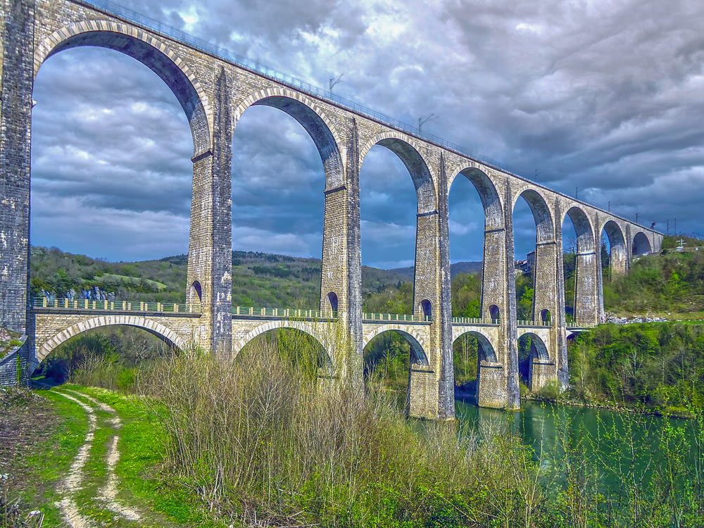 a large stone bridge over a river under a cloudy sky