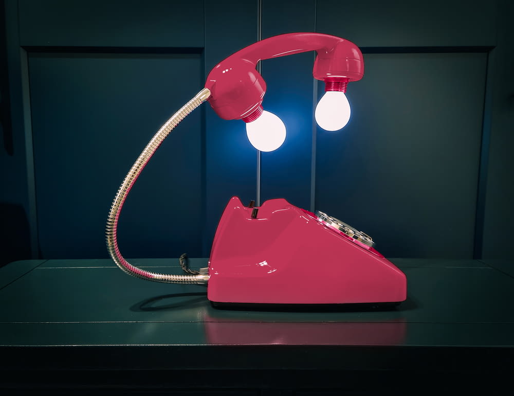 Un teléfono rosa sentado encima de una mesa
