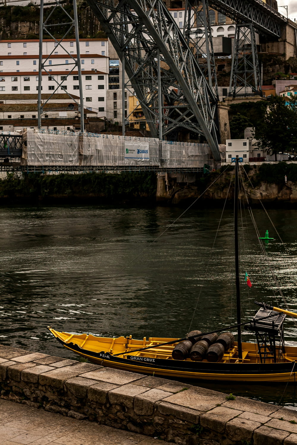 a yellow boat sitting on top of a river next to a bridge