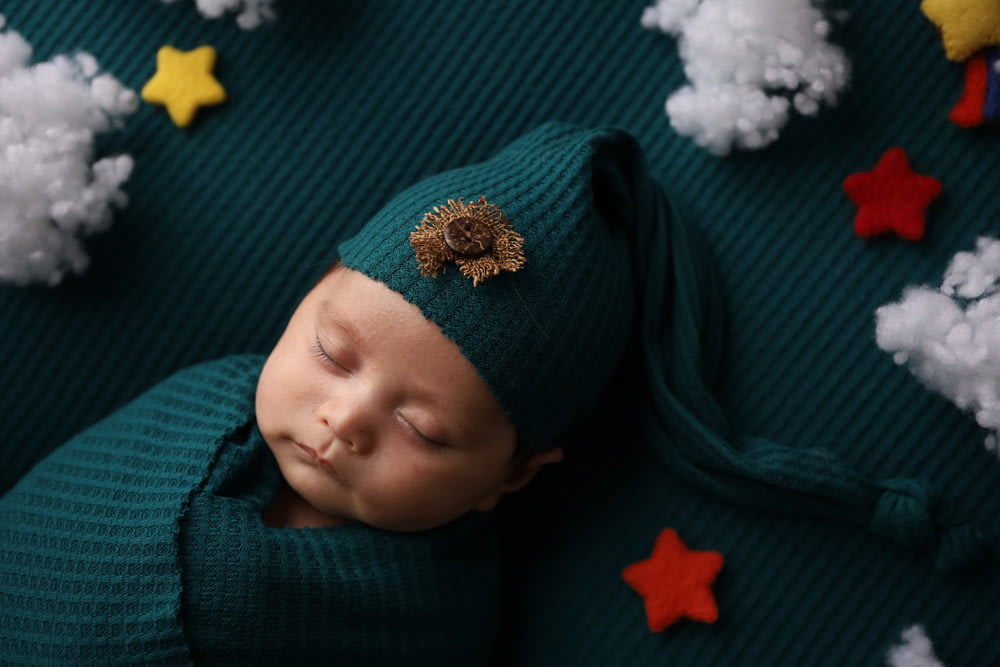 a newborn baby wearing a green hat and green sweater