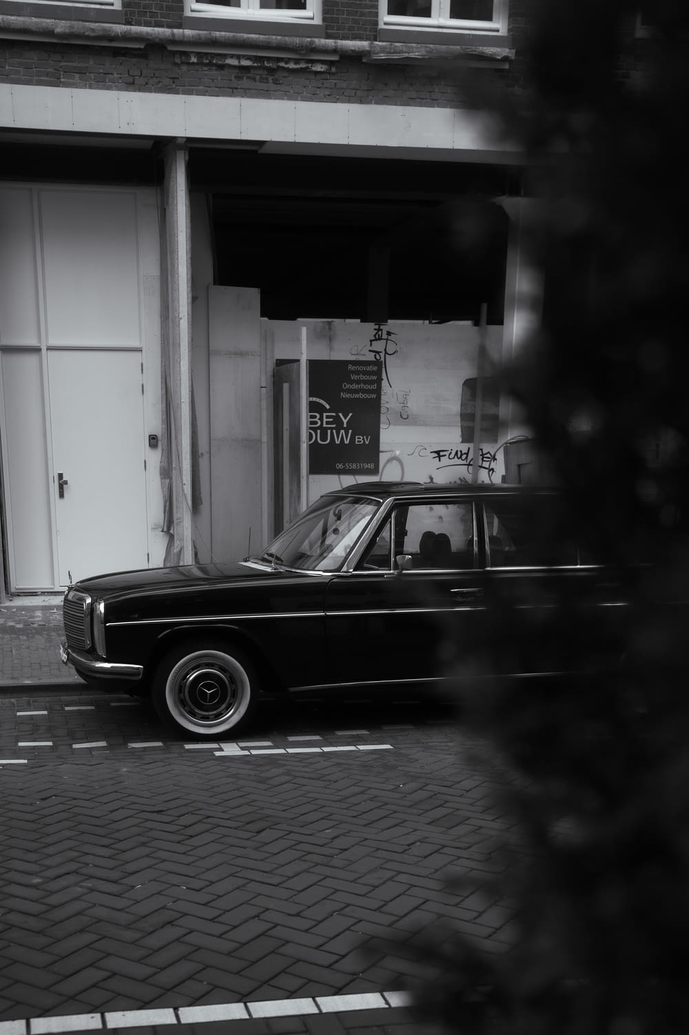 a black and white photo of a car parked in front of a building