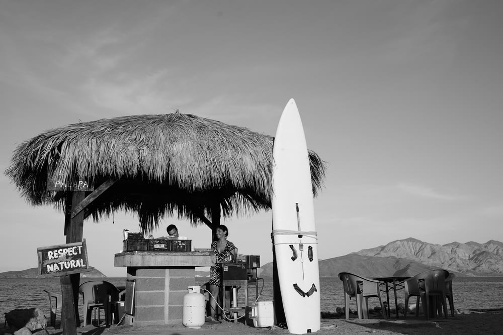 a man sitting at a table next to a surfboard