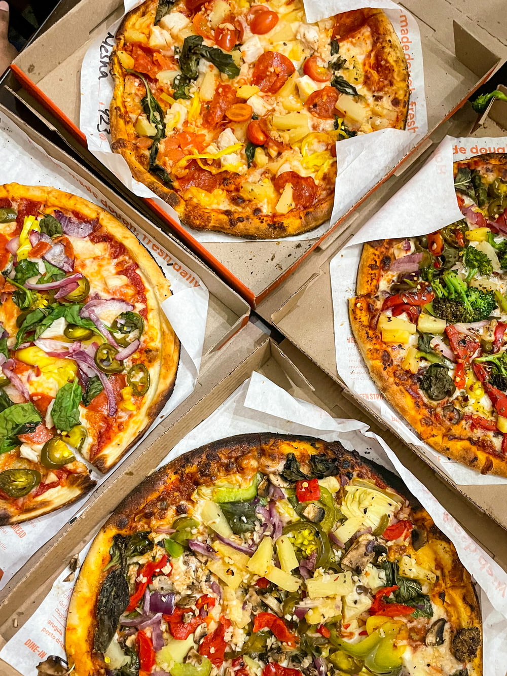 four pizzas with different toppings in a box