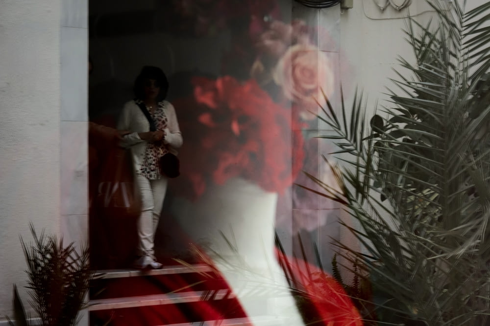a mannequin in a red and white dress with a red rose behind it
