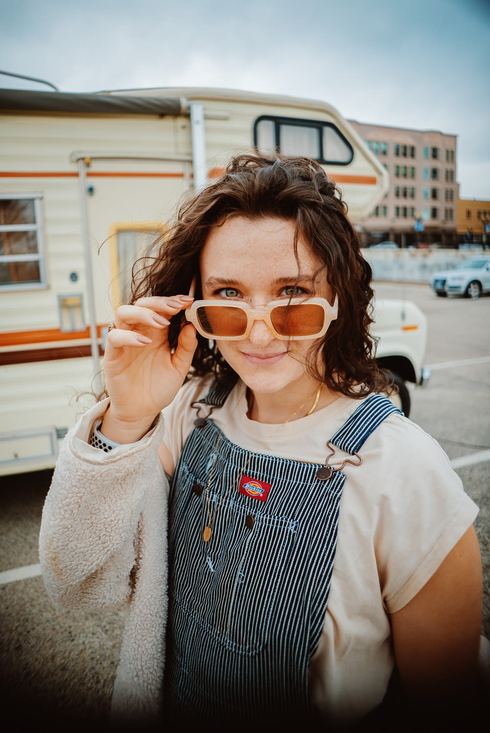 a woman in overalls holding up a pair of sunglasses