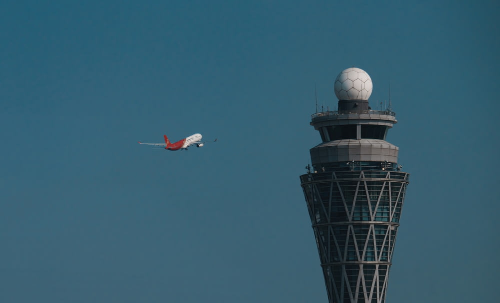 an airplane is flying by a control tower