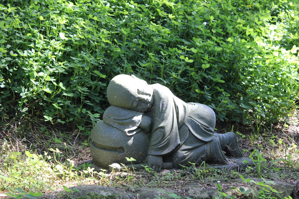 a statue of a person laying on top of a pile of rocks