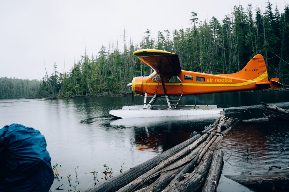 an orange and yellow plane sitting on top of a body of water