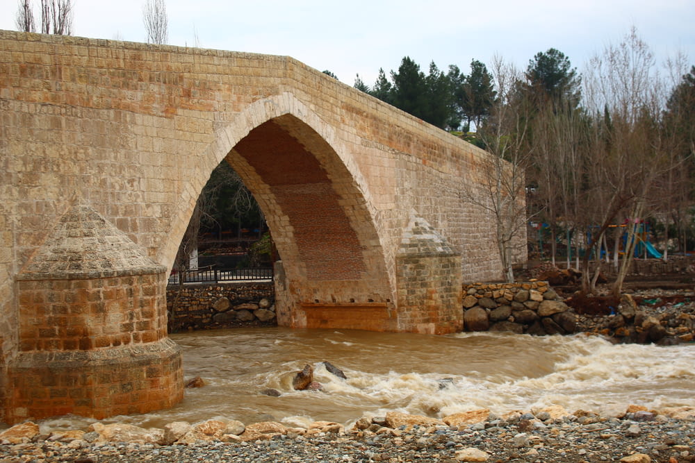 a stone bridge over a river with water rushing under it