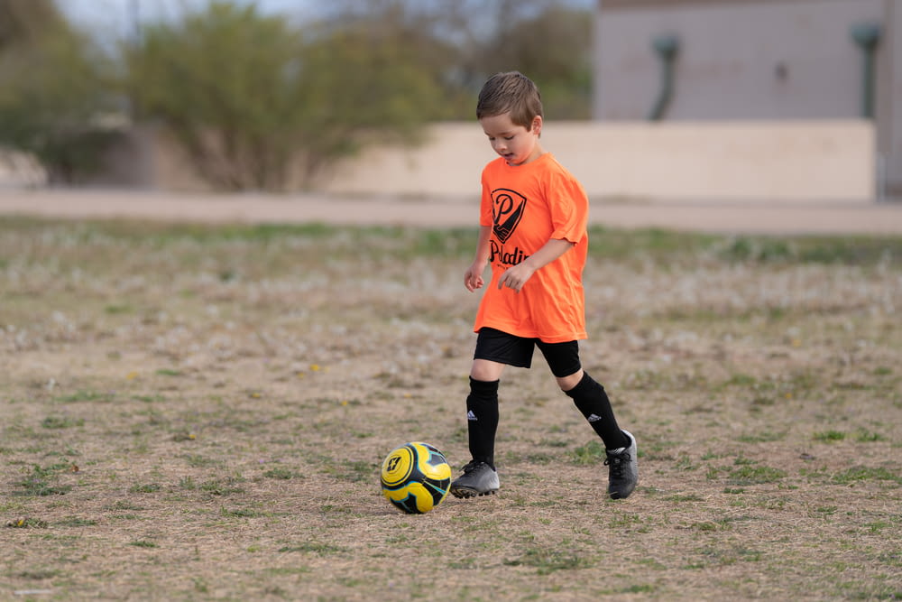 a young boy kicking a soccer ball on a field