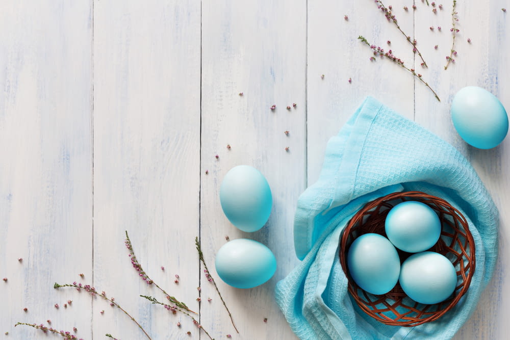 un panier rempli d’œufs bleus sur une table en bois