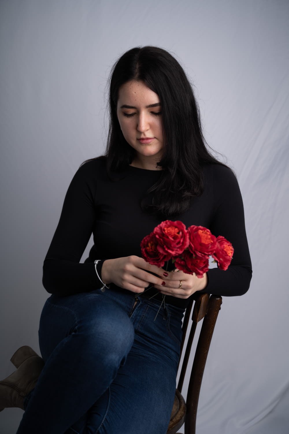 a woman sitting in a chair holding a bunch of flowers