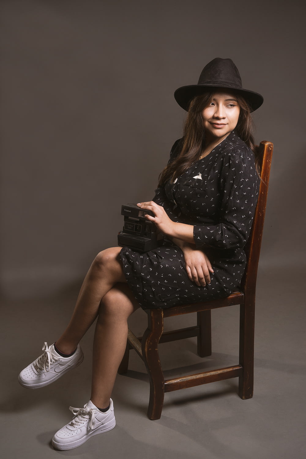 a girl in a black dress and hat sitting on a chair